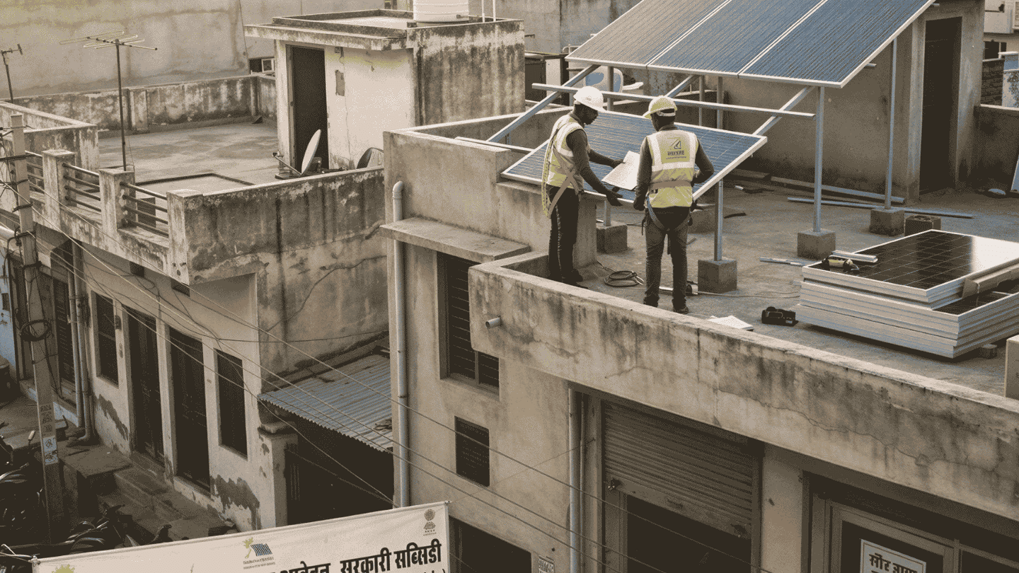 Workers install rooftop solar panels in an Indian neighbourhood.